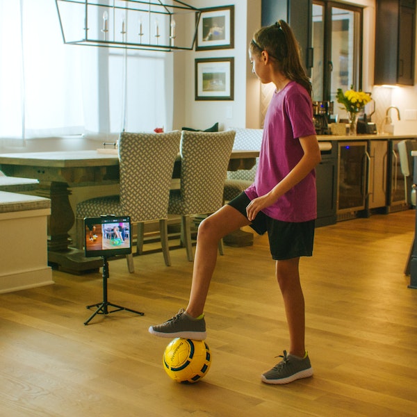 youth soccer player with dribbleup smart soccer ball and tablet