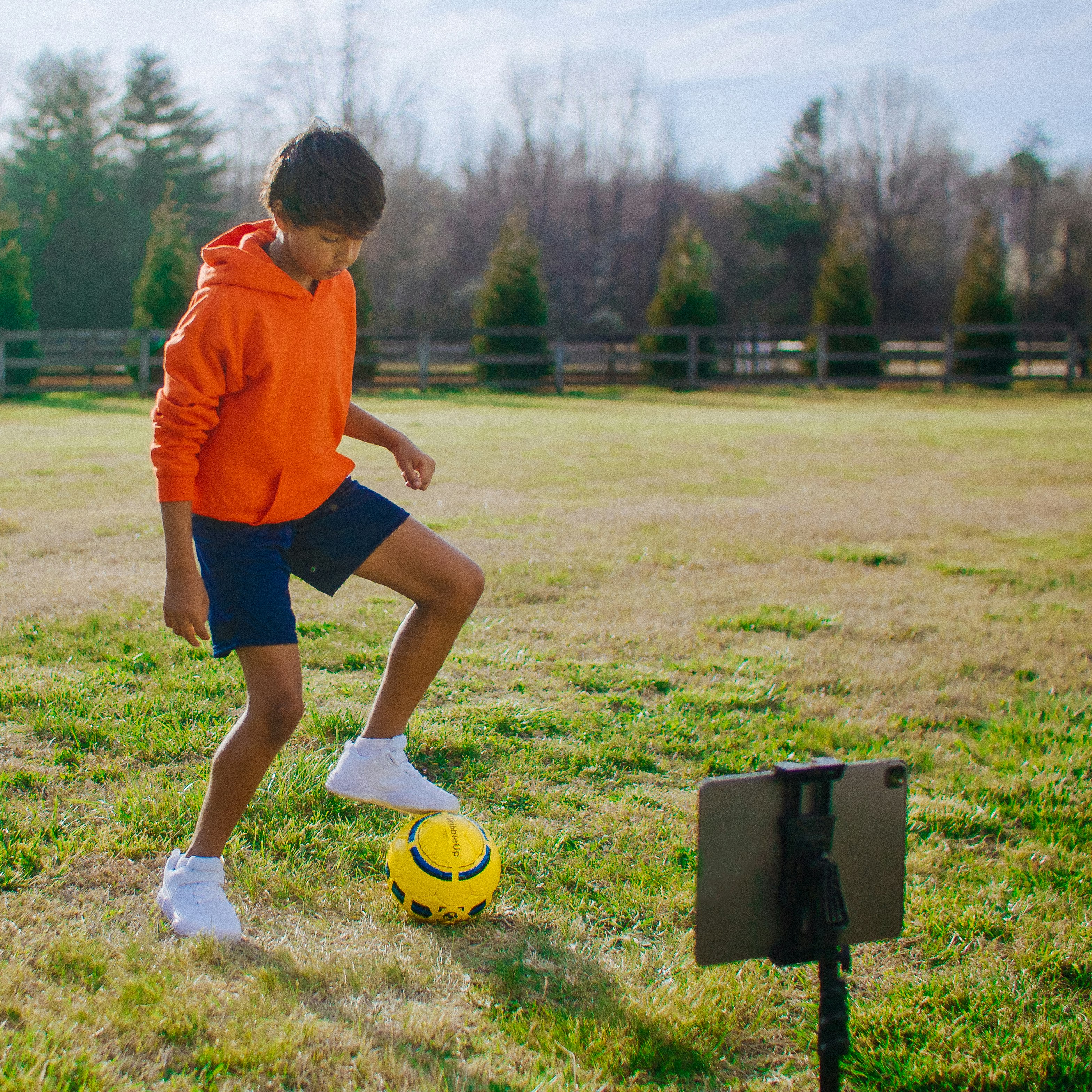 Young child training with a soccer ball in his yard.