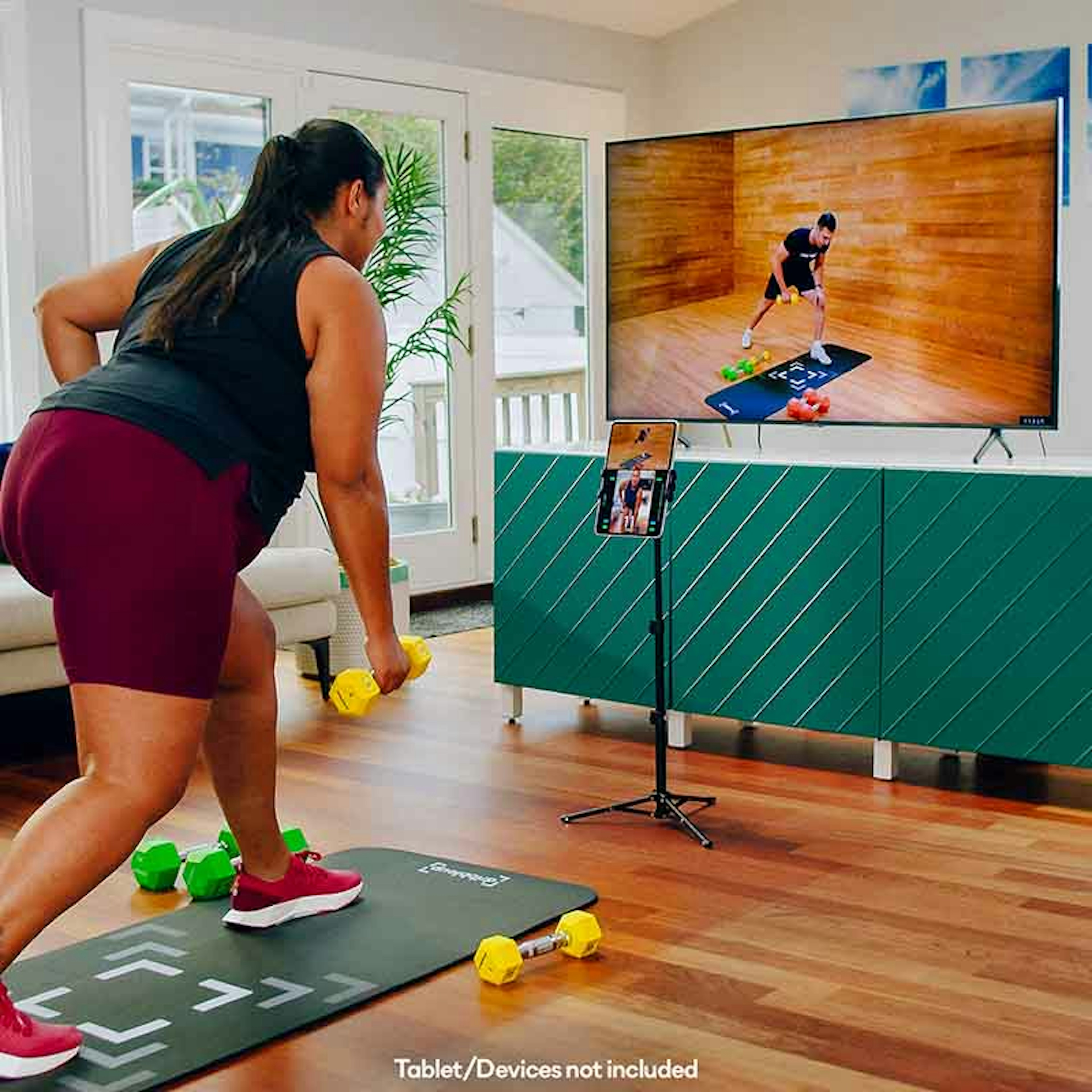 Woman using smart weights with tablet and TV