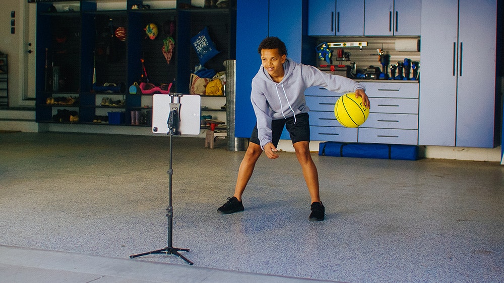 Young kid practicing his basketball dribbling in the garage.