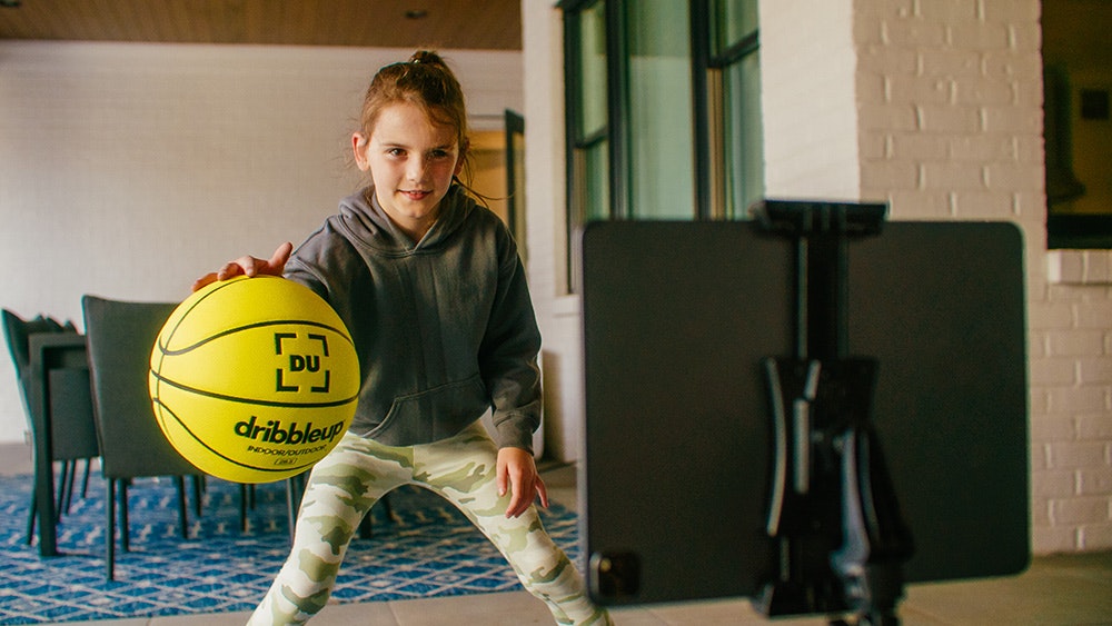 A young girl practices at home with the Smart Basketball.