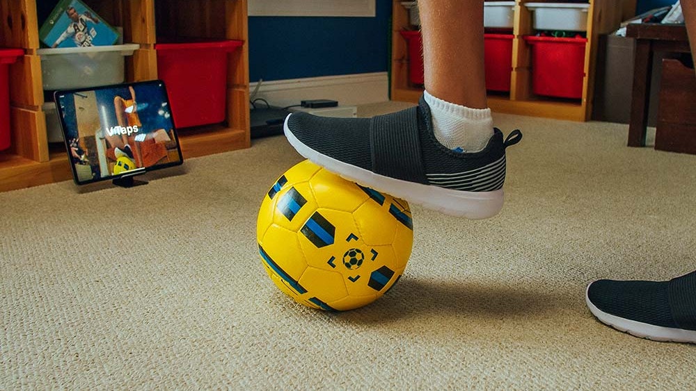 smart soccer ball at a player's feet and tablet with dribbleup app