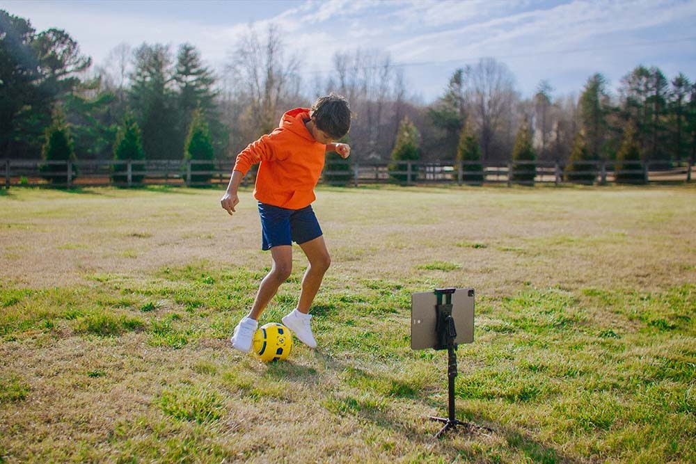 youth soccer player with dribbleup smart soccer ball and tablet