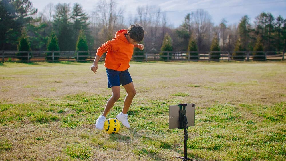 youth soccer player with dribbleup smart soccer ball and tablet
