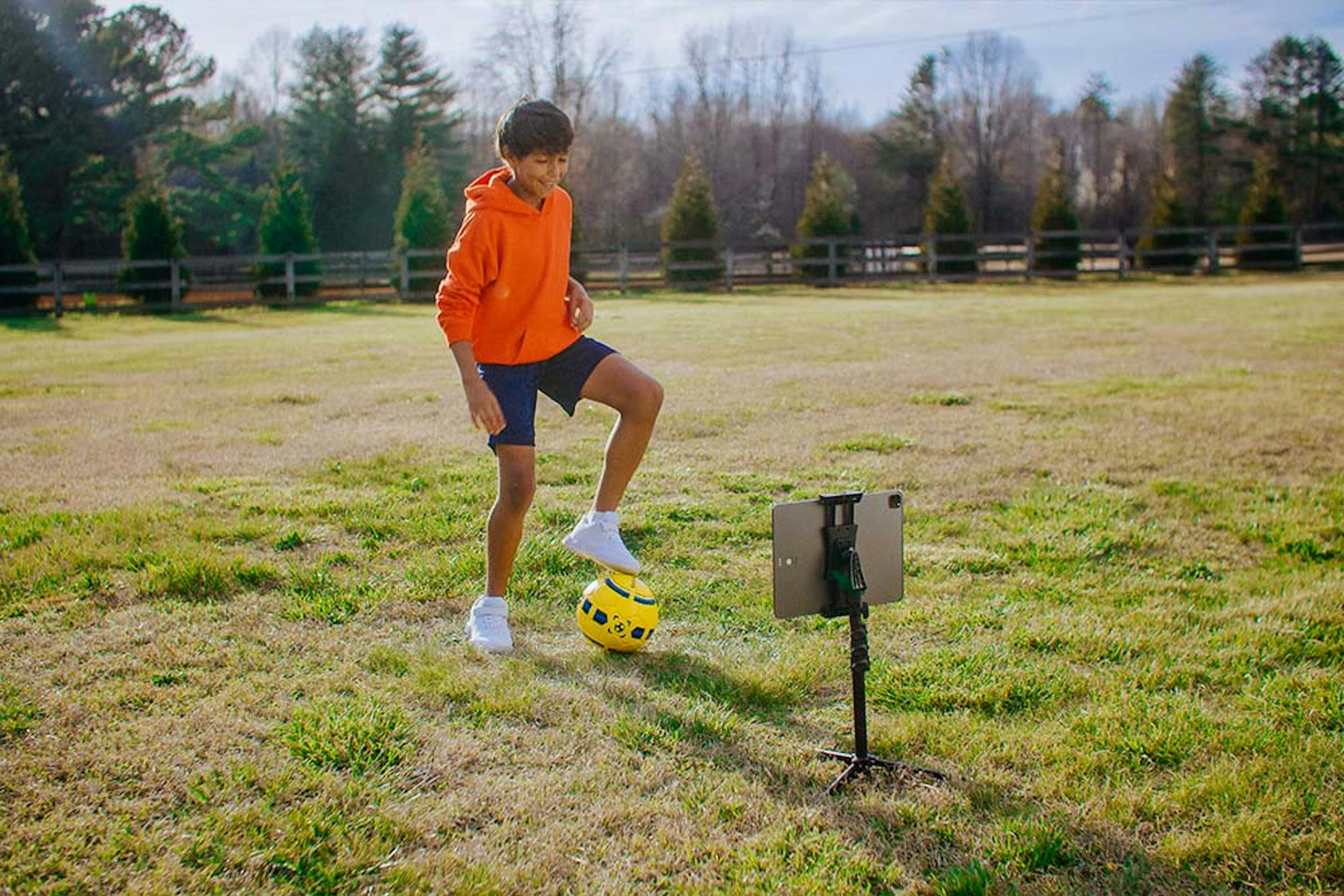Young boy practices with the Smart Soccer Ball in his yard at home.