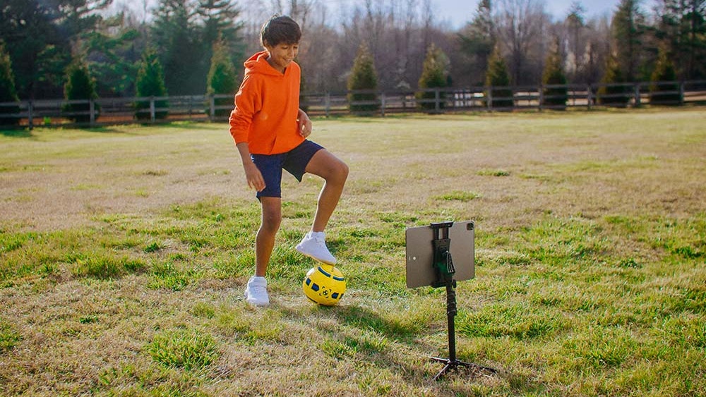 Young boy practices with the Smart Soccer Ball in his yard at home.