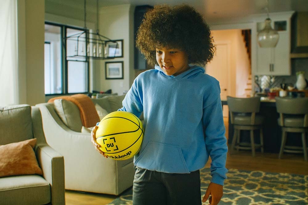 Young boy practicing in his living room with the Smart Basketball.