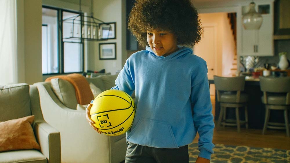 Young boy practicing in his living room with the Smart Basketball.