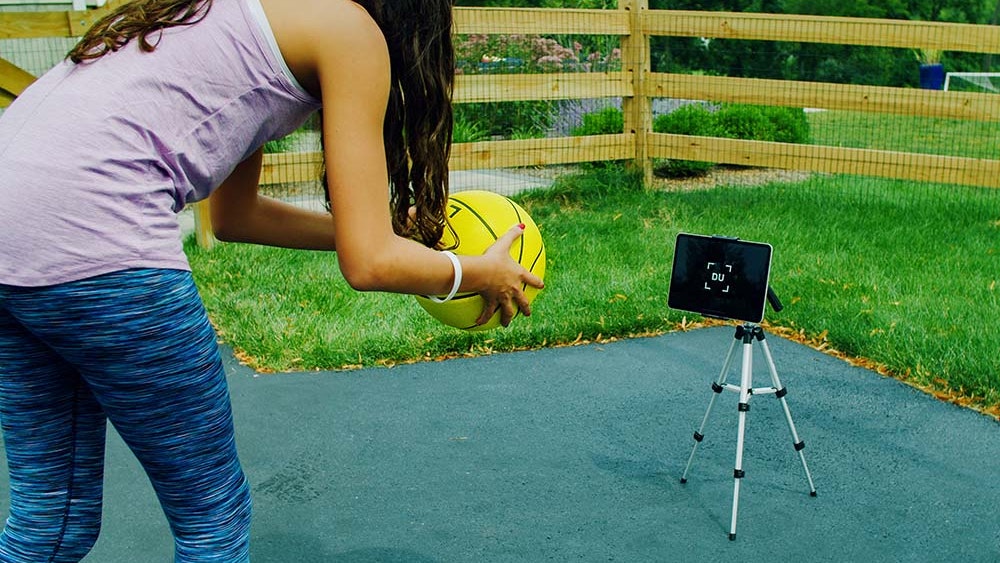 Young girl practices in her driveway with the Smart Basketball.