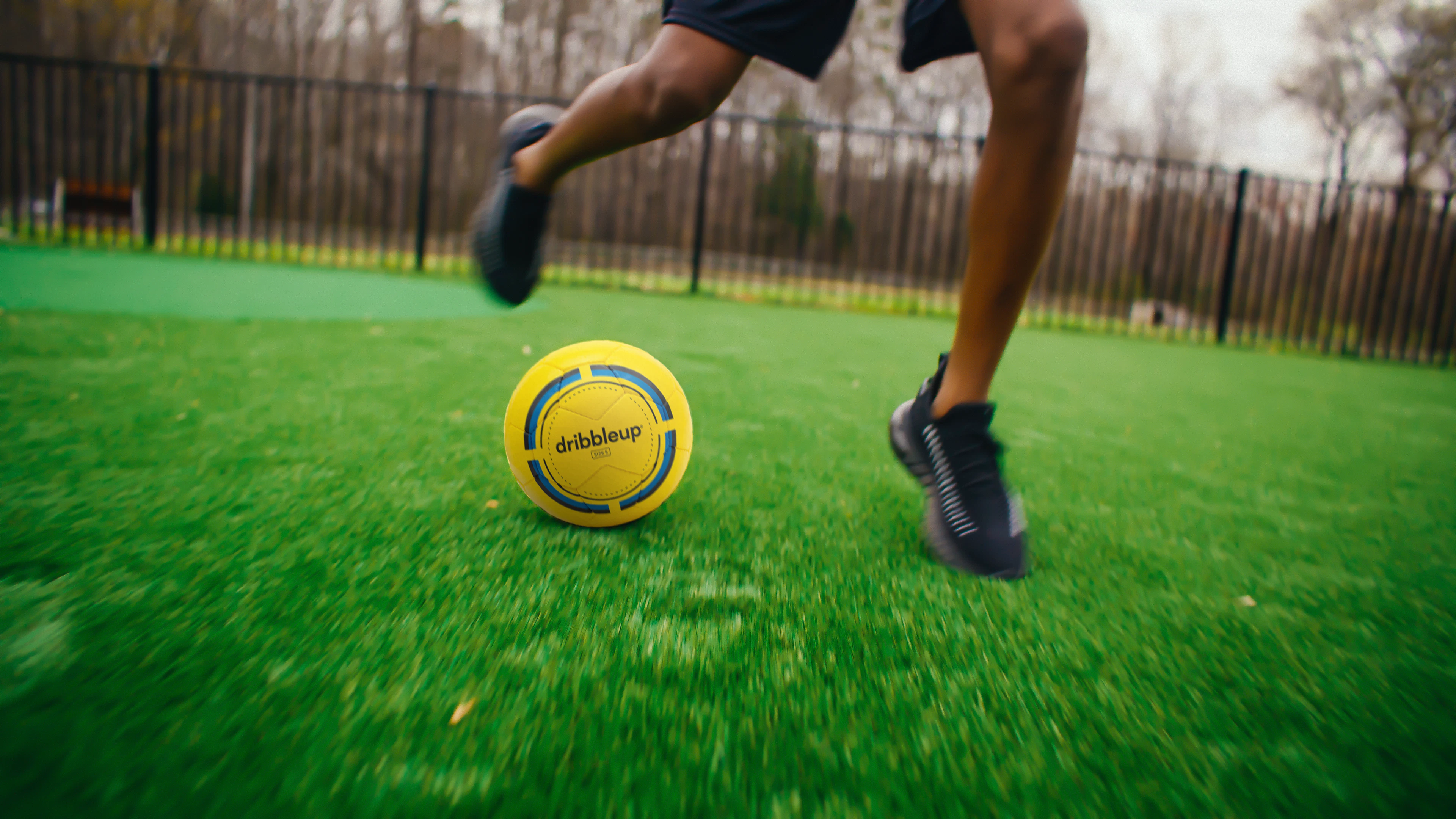 Player dribbling a Dribbleup Smart Soccer Ball at speed on backyard turf