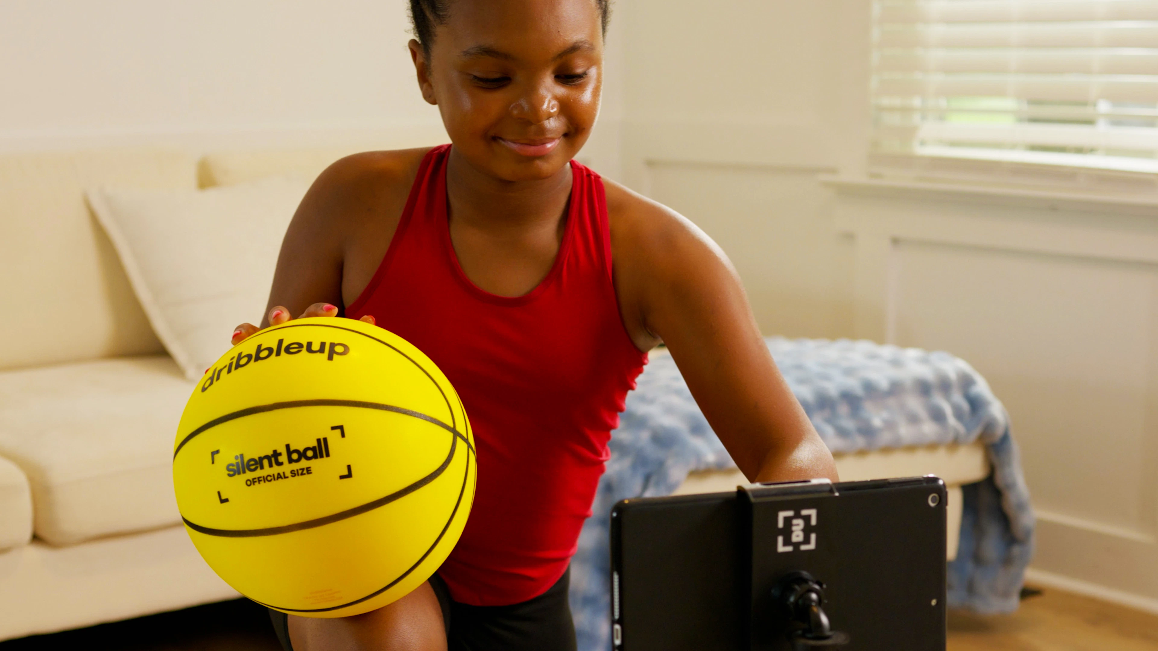 Close-up of the yellow Dribbleup Silent Smart Basketball marked OFFICIAL SIZE held by a young player